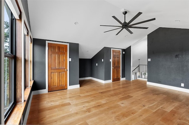 unfurnished living room featuring light wood-style flooring, ceiling fan, high vaulted ceiling, and baseboards