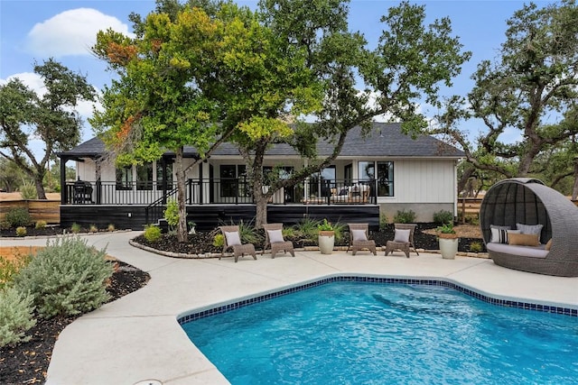 outdoor pool with a wooden deck and a patio