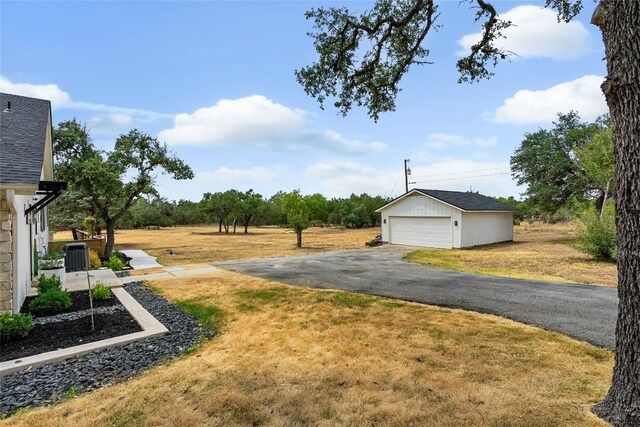 view of yard with a detached garage and an outbuilding