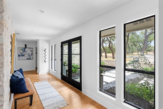 entryway with a wealth of natural light, french doors, baseboards, and light wood finished floors