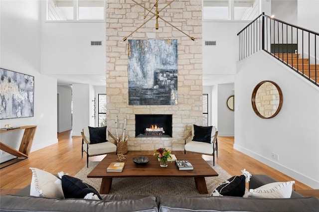 living area with a towering ceiling, a fireplace, wood finished floors, baseboards, and stairs