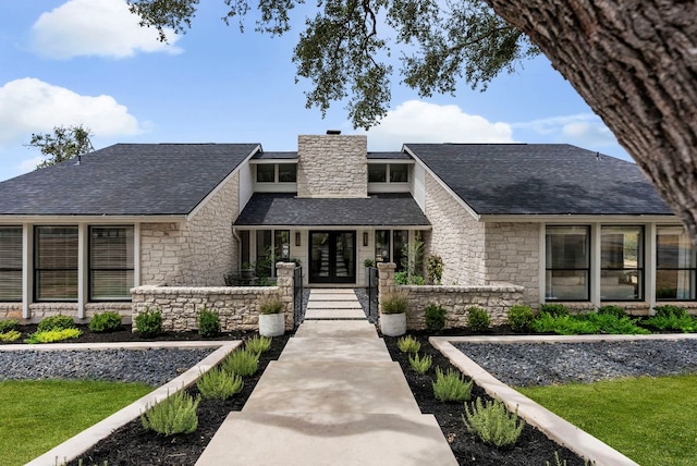 view of front of home with french doors, stone siding, and a shingled roof