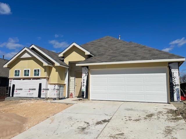 view of front of house featuring stucco siding, concrete driveway, a garage, and a shingled roof