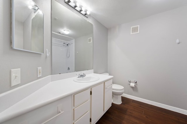 bathroom featuring visible vents, toilet, wood finished floors, baseboards, and walk in shower