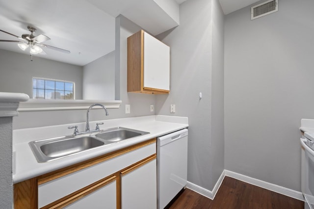 kitchen with visible vents, white dishwasher, a sink, dark wood-type flooring, and light countertops