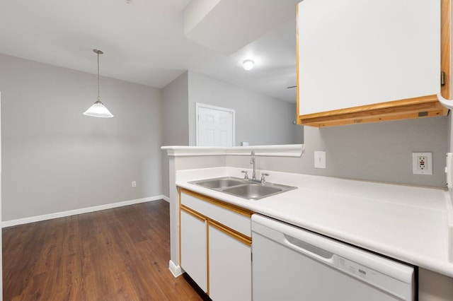 kitchen with a sink, white dishwasher, light countertops, baseboards, and hanging light fixtures