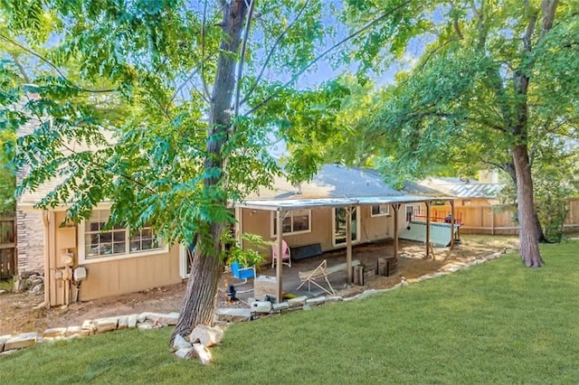 back of house featuring stone siding, a patio, a yard, and fence