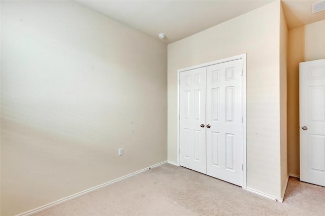 unfurnished bedroom with baseboards, a closet, and light carpet