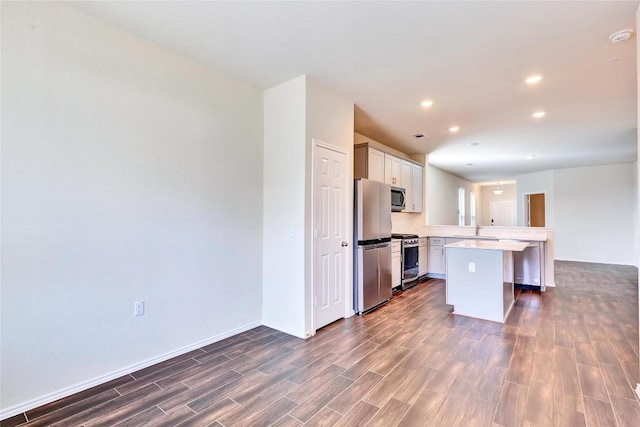 kitchen featuring a peninsula, light countertops, dark wood-style floors, and appliances with stainless steel finishes