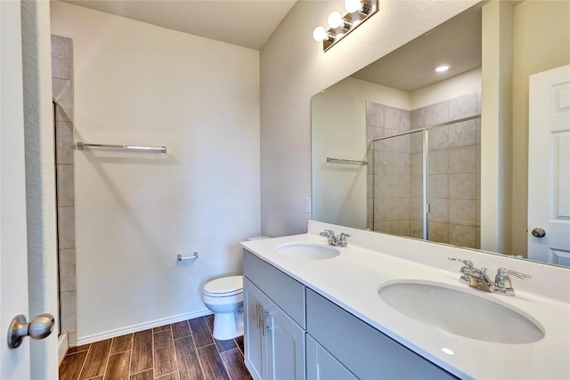 bathroom featuring a shower stall, toilet, wood finish floors, and a sink