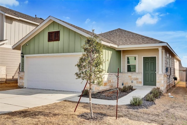 10309 American Paint Way, Manor, TX 78653 - view of front facade featuring a shingled roof, an attached garage, stone siding, driveway, and board and batten siding