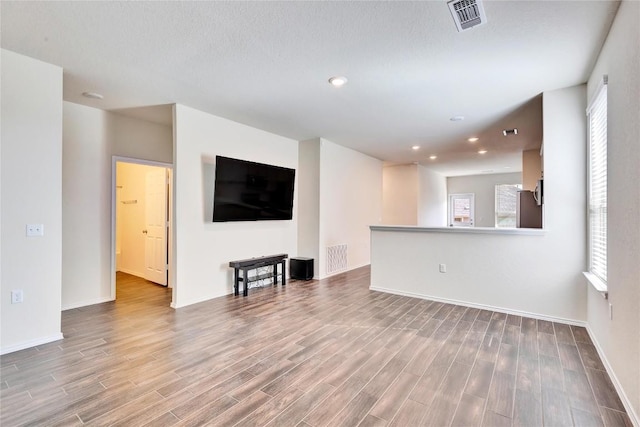 unfurnished living room with visible vents, recessed lighting, baseboards, and wood finished floors