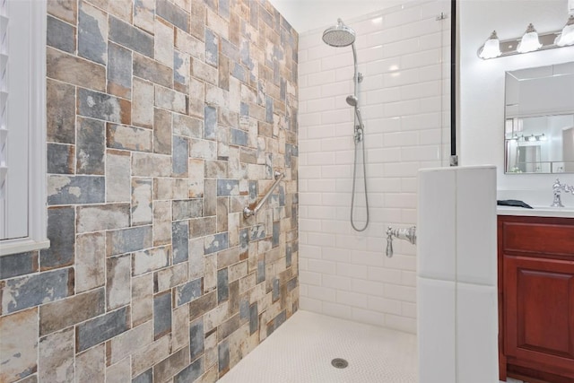 full bathroom featuring tiled shower and vanity