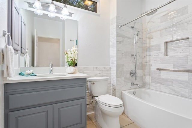 bathroom with tile patterned floors, toilet, tile walls,  shower combination, and vanity