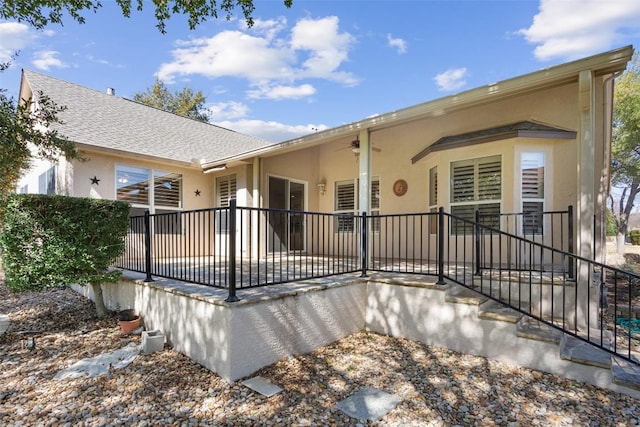 view of front of property featuring a patio area, stucco siding, a shingled roof, and a ceiling fan