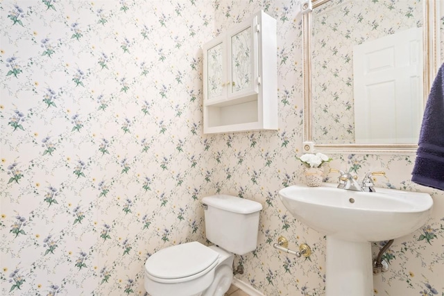 half bathroom featuring toilet, wallpapered walls, and baseboards