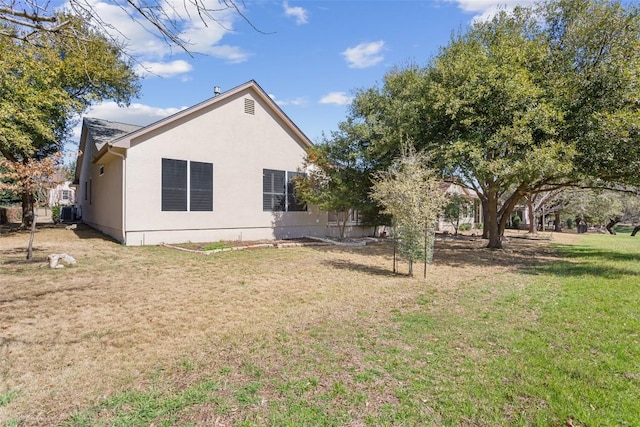 rear view of house with a lawn and stucco siding