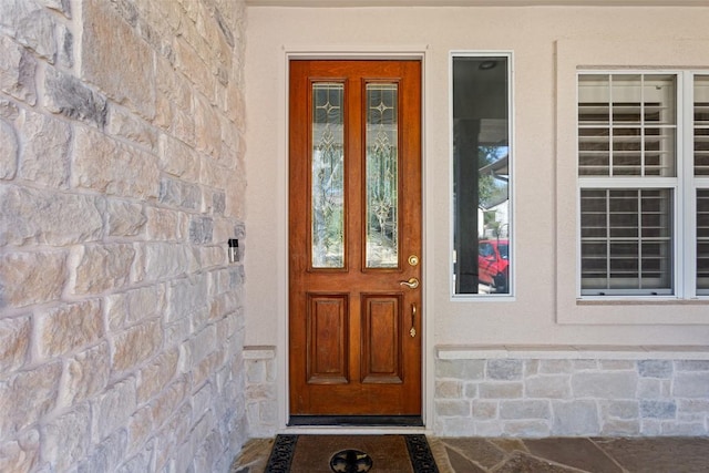 property entrance with stone siding and stucco siding