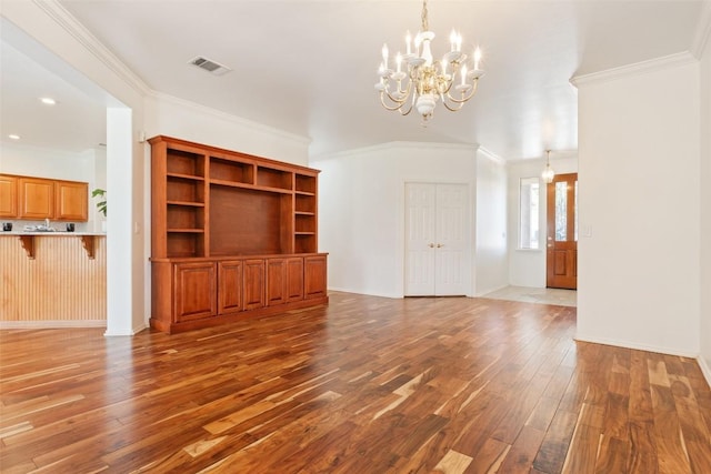 unfurnished living room featuring visible vents, baseboards, an inviting chandelier, hardwood / wood-style flooring, and crown molding