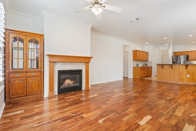 unfurnished living room with visible vents, light wood-style floors, a glass covered fireplace, and crown molding