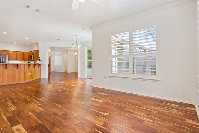 unfurnished living room featuring visible vents, ornamental molding, ceiling fan with notable chandelier, wood finished floors, and baseboards