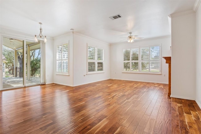 unfurnished living room with wood finished floors, baseboards, visible vents, ornamental molding, and ceiling fan with notable chandelier