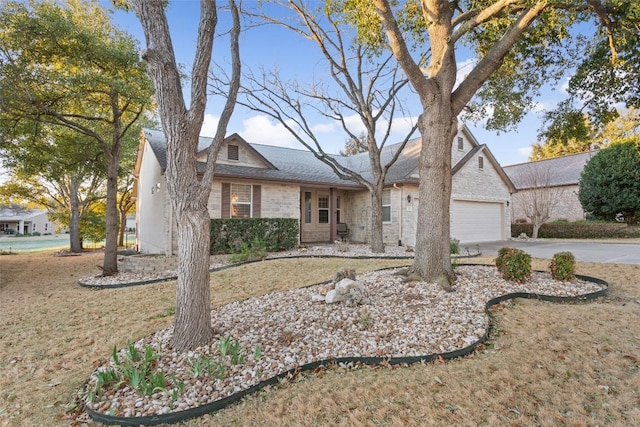 view of front of house featuring stone siding, driveway, and an attached garage