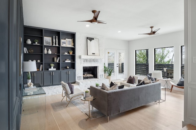 living area with a brick fireplace, french doors, a ceiling fan, and light wood finished floors