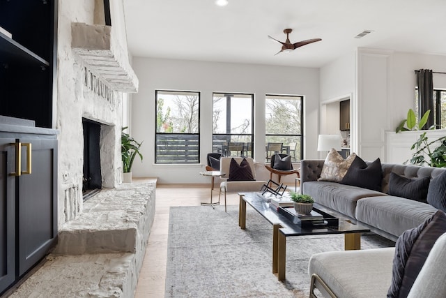 living area with wood finished floors, visible vents, and a high end fireplace