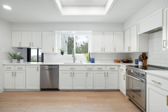 kitchen with a sink, stainless steel appliances, light wood-style floors, and white cabinets