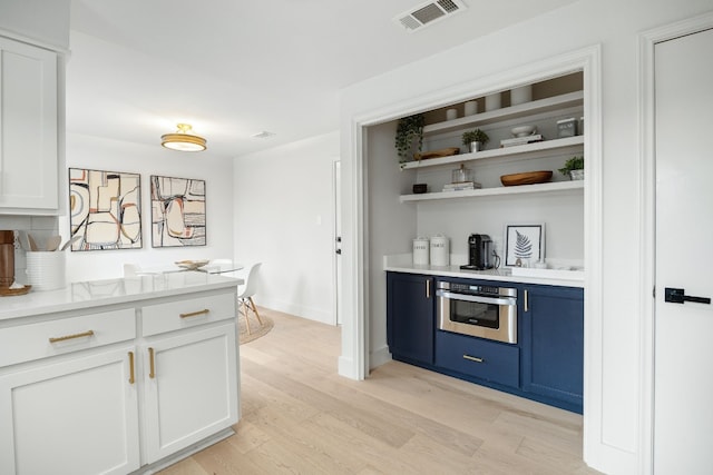 bar with oven, visible vents, baseboards, and light wood-style floors