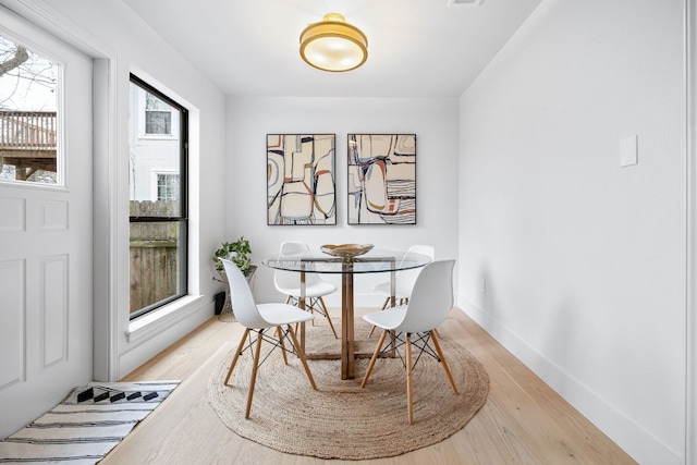 dining room with light wood-style flooring, visible vents, and baseboards