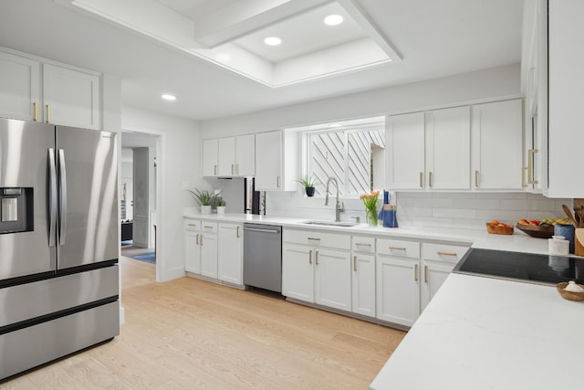 kitchen with a sink, stainless steel appliances, light wood-style floors, and white cabinetry