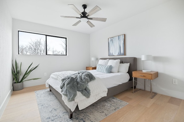 bedroom with ceiling fan, baseboards, and light wood-style flooring