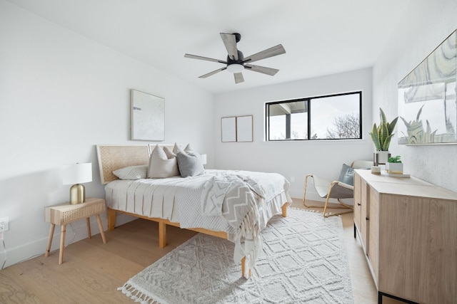 bedroom with a ceiling fan, light wood-type flooring, and baseboards