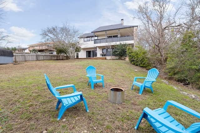 view of community featuring a fire pit, fence, a yard, an outdoor structure, and a storage unit