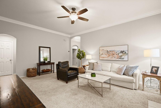 carpeted living area with arched walkways, ceiling fan, and ornamental molding