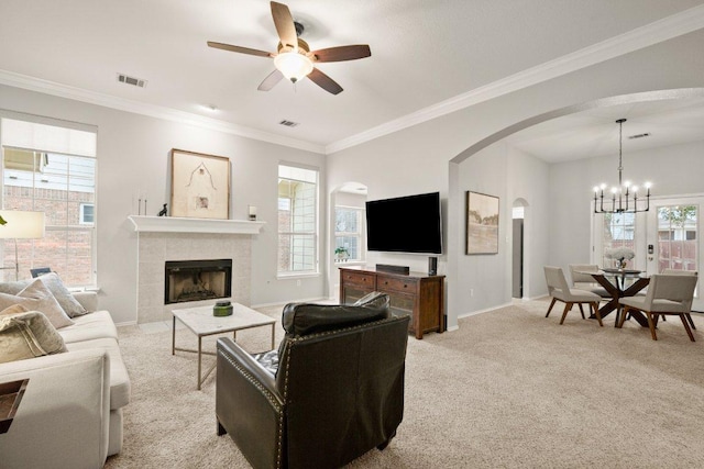 living area featuring visible vents, baseboards, a tile fireplace, crown molding, and light colored carpet