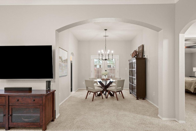 dining area featuring arched walkways, light colored carpet, baseboards, and an inviting chandelier