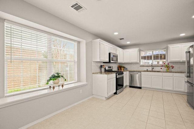 kitchen with visible vents, a sink, tasteful backsplash, white cabinetry, and stainless steel appliances