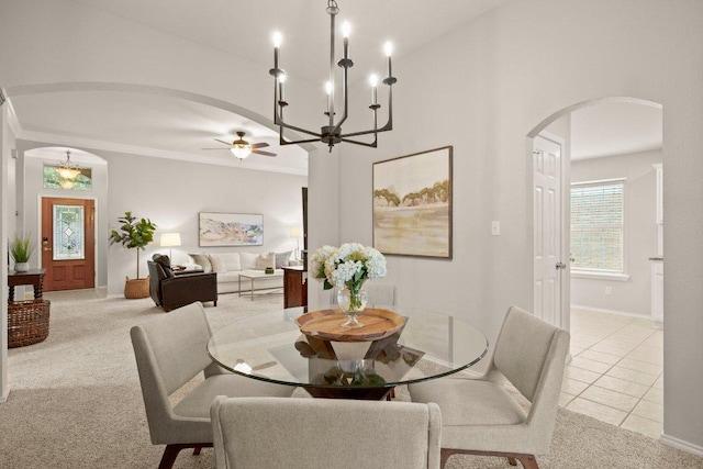 tiled dining room featuring baseboards, arched walkways, ceiling fan, crown molding, and carpet flooring