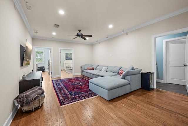 living area with visible vents, crown molding, baseboards, and wood finished floors