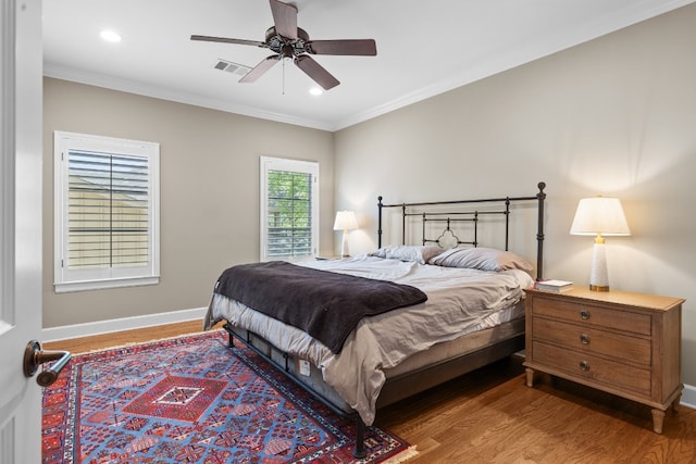 bedroom featuring visible vents, crown molding, baseboards, and wood finished floors