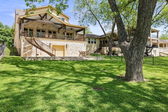 back of house featuring a fenced backyard, a lawn, ceiling fan, and stairs