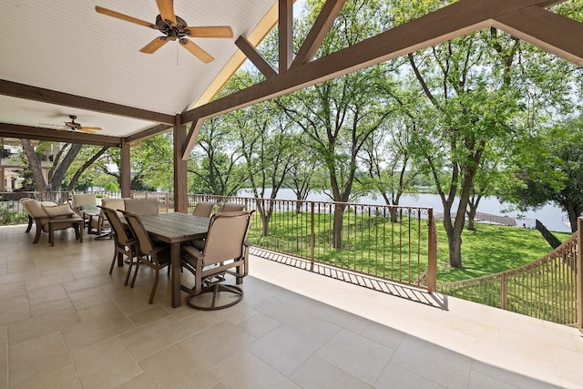 view of patio featuring outdoor dining area, a water view, fence private yard, and a ceiling fan