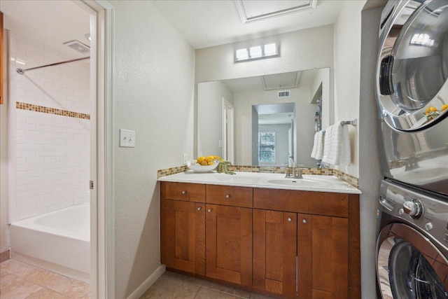 full bath featuring stacked washer and clothes dryer, tile patterned flooring, a textured wall, vanity, and baseboards