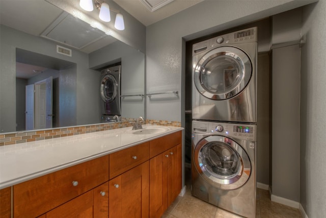 laundry area featuring attic access, a sink, visible vents, stacked washer / drying machine, and laundry area