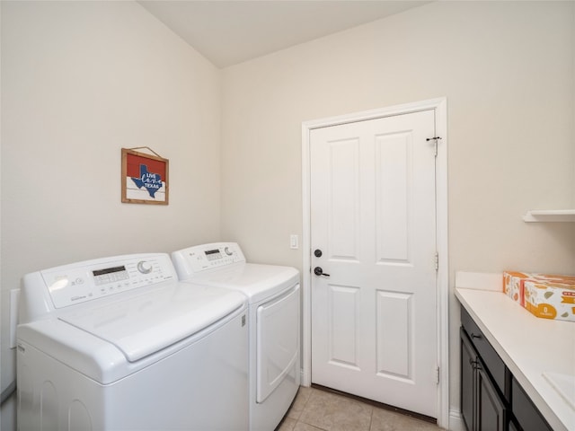 laundry area featuring washing machine and clothes dryer, light tile patterned floors, and cabinet space