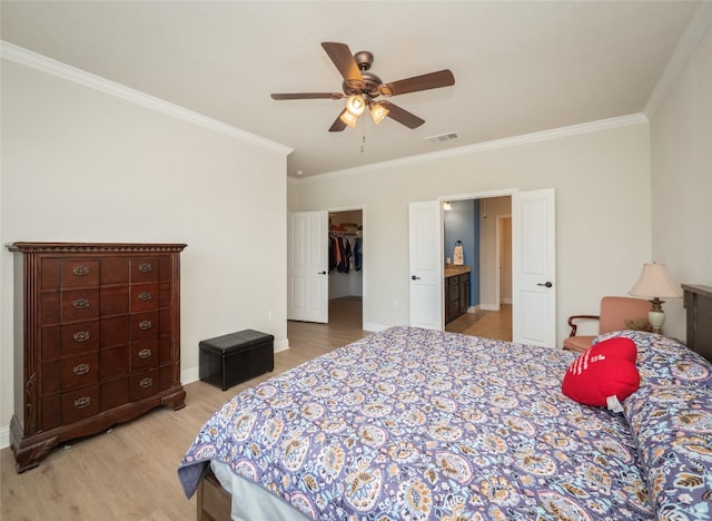 bedroom with a walk in closet, crown molding, visible vents, and light wood finished floors