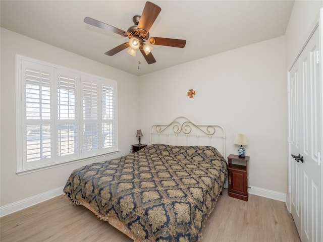 bedroom with light wood-type flooring, a closet, baseboards, and a ceiling fan